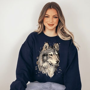 Pu&ograve; includere: Una felpa blu navy con una grafica di lupo in stile acquerello sul davanti. Il lupo &egrave; grigio e bianco con il naso e gli occhi neri.