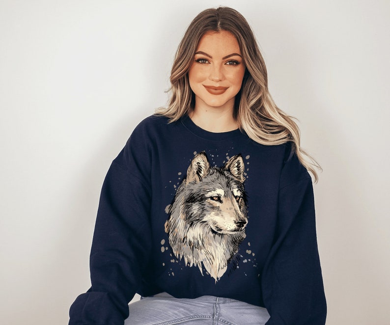 Pu&ograve; includere: Una felpa blu navy con una grafica di lupo in stile acquerello sul davanti. Il lupo &egrave; grigio e bianco con il naso e gli occhi neri.
