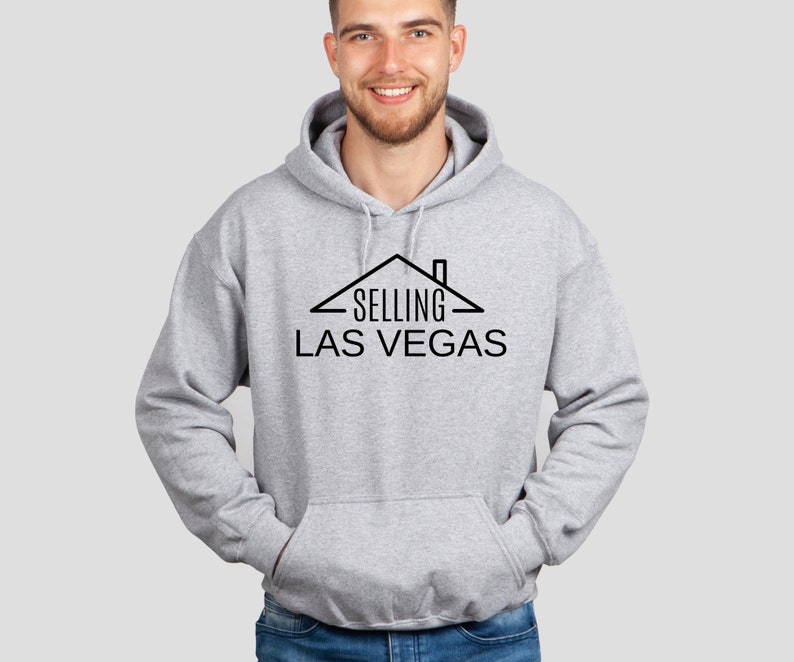 May include: A gray hooded sweatshirt with a black graphic design of a house with the text "SELLING LAS VEGAS" underneath.