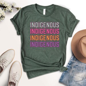 May include: A green t-shirt with the word "INDIGENOUS" repeated four times in different colors: light green, pink, orange, and purple.