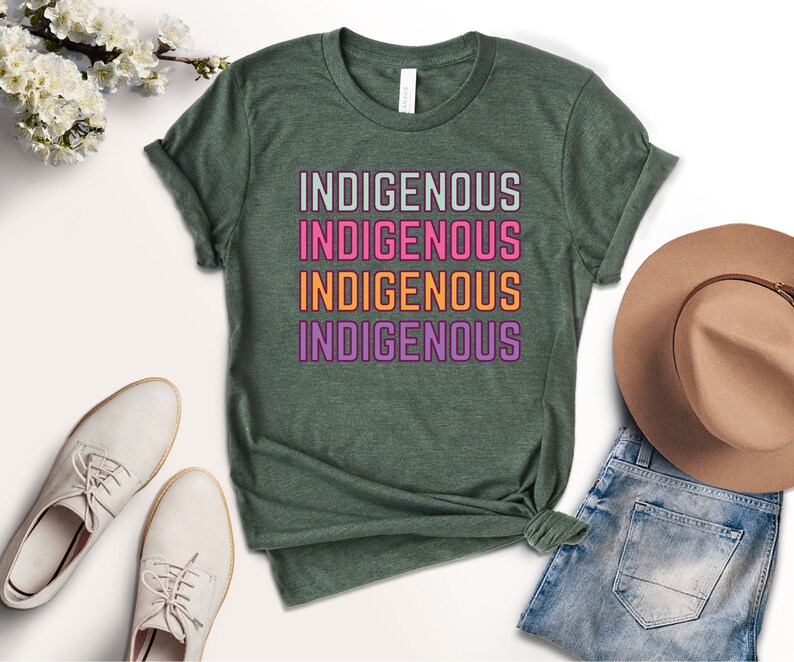 May include: A green t-shirt with the word "INDIGENOUS" repeated four times in different colors: light green, pink, orange, and purple.