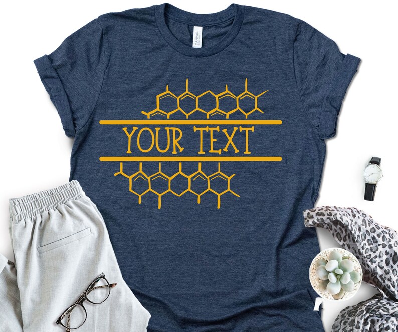 K&ouml;nnte beinhalten: Ein marineblaues T-Shirt mit einem Wabenmuster und dem Text "YOUR TEXT" in Gelb.