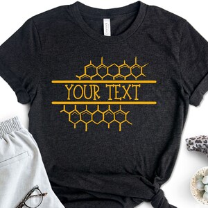 K&ouml;nnte beinhalten: Ein schwarzes T-Shirt mit einem goldenen Wabenmuster und dem aufgedruckten Text "YOUR TEXT".