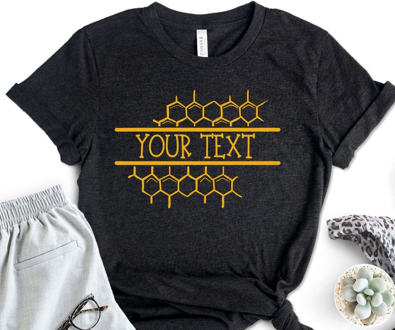 K&ouml;nnte beinhalten: Ein schwarzes T-Shirt mit einem goldenen Wabenmuster und dem aufgedruckten Text "YOUR TEXT".