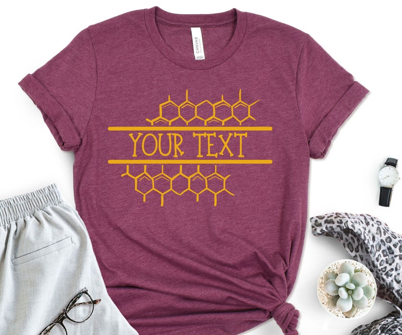 K&ouml;nnte beinhalten: Ein maroonfarbenes T-Shirt mit einem Wabenmuster und dem Text "YOUR TEXT" in Gelb.
