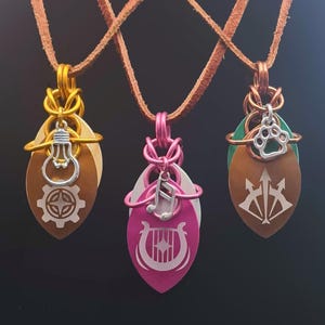 May include: Three pendant necklaces with brown leather cords. Each pendant features a layered design with metal charms. One has a lightbulb and gear, another a musical note and lyre, and the last a paw print and trident.