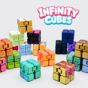 May include: A collection of multi-colored infinity cubes in various shades including gold, green, orange, blue, pink, purple, and black. The cubes are arranged in a group, and the text "INFINITY CUBES" is displayed in a stylized font above them.