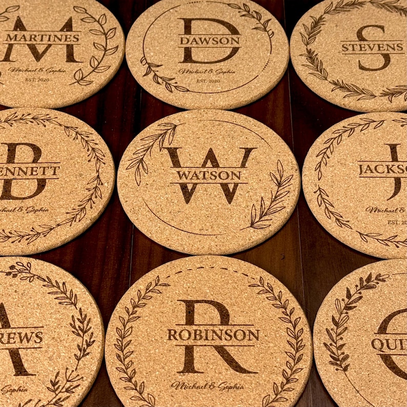 May include: Set of ten round cork coasters with personalized names and initials. Each coaster features a decorative wreath design with a single initial in the center and the name below. The names include Martines, Dawson, Stevens, Bennett, Watson, Jackson, Andrews, Robinson, and Quinn.