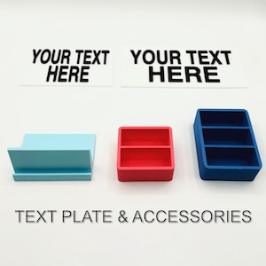 May include: Two white rectangular text plates with the text "YOUR TEXT HERE" on each. There are three small storage containers: one light blue, one red, and one blue.