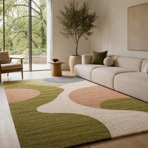 K&ouml;nnte beinhalten: Ein gro&szlig;er, rechteckiger Teppich mit einem abstrakten Design. Der Teppich hat ein wellenf&ouml;rmiges Muster mit gr&uuml;nen, pfirsichfarbenen, grauen und cremefarbenen Abschnitten. Der Teppich liegt auf einem Holzboden in einem Wohnzimmer.