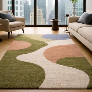 K&ouml;nnte beinhalten: Ein rechteckiger Teppich mit modernem Design. Der Teppich hat ein flie&szlig;endes Muster aus olivgr&uuml;nen, pfirsichfarbenen, cremewei&szlig;en und blauen Formen. Der Teppich liegt auf einem Holzboden in einem Wohnzimmer.