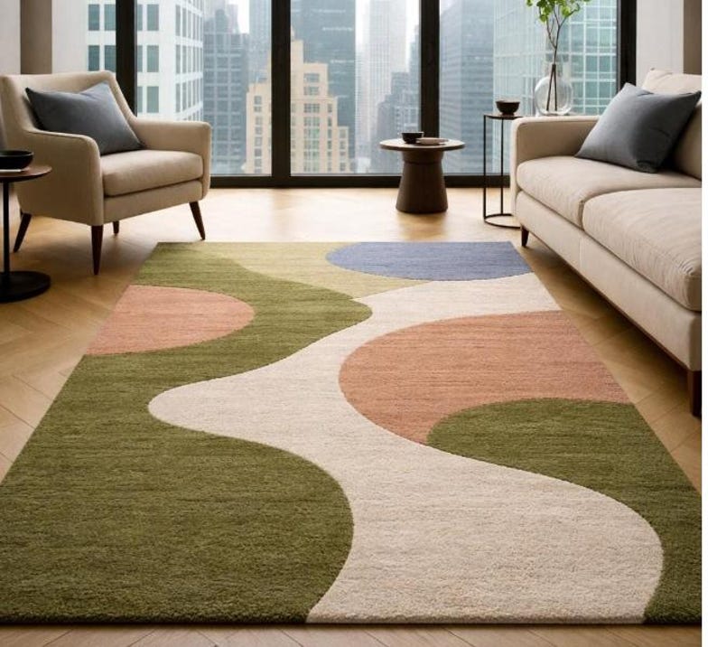 K&ouml;nnte beinhalten: Ein rechteckiger Teppich mit modernem Design. Der Teppich hat ein flie&szlig;endes Muster aus olivgr&uuml;nen, pfirsichfarbenen, cremewei&szlig;en und blauen Formen. Der Teppich liegt auf einem Holzboden in einem Wohnzimmer.