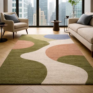 K&ouml;nnte beinhalten: Rechteckiger Teppich mit abstraktem Design. Der Teppich hat ein flie&szlig;endes Muster aus olivgr&uuml;nen, pfirsichfarbenen, wei&szlig;en und blauen Formen. Er liegt auf einem Holzboden in einem Wohnzimmer.