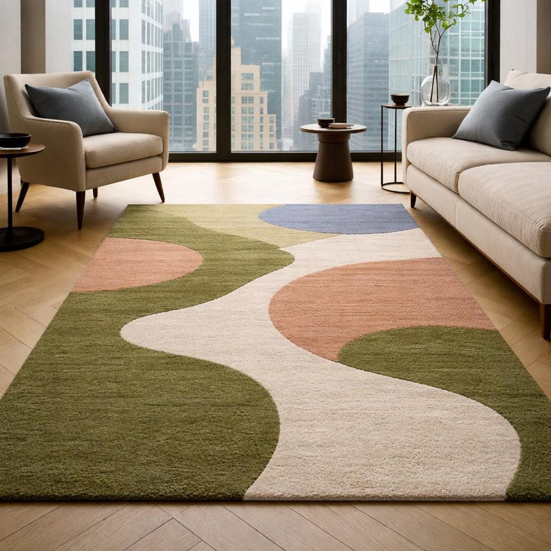 K&ouml;nnte beinhalten: Rechteckiger Teppich mit abstraktem Design. Der Teppich hat ein flie&szlig;endes Muster aus olivgr&uuml;nen, pfirsichfarbenen, wei&szlig;en und blauen Formen. Er liegt auf einem Holzboden in einem Wohnzimmer.