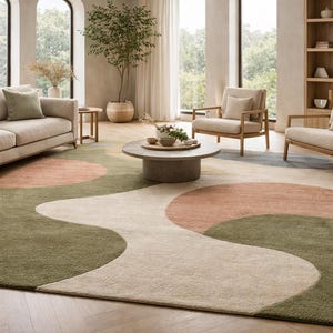 K&ouml;nnte beinhalten: Ein Wohnzimmer mit beigem Sofa, zwei Sesseln und einem runden Couchtisch. Der Boden ist mit einem gro&szlig;en Teppich mit wellenf&ouml;rmigem Design in Gr&uuml;n-, Pfirsich- und Beiget&ouml;nen bedeckt. Der Raum hat gro&szlig;e Fenster und ein B&uuml;cherregal aus Holz.