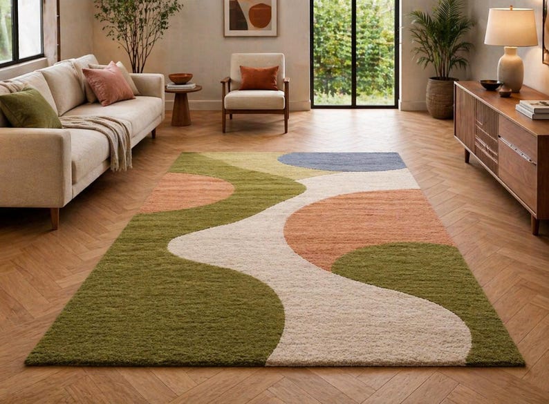 K&ouml;nnte beinhalten: Ein rechteckiger Teppich mit einem abstrakten Design in Gr&uuml;n, Pfirsich, Blau und Creme. Der Teppich hat ein wellenf&ouml;rmiges Muster und liegt auf einem Holzboden, was dem Wohnzimmer eine moderne Note verleiht. Ungef&auml;hre Abmessungen: 200 cm x 300 cm.