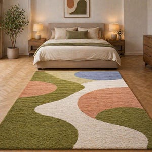 K&ouml;nnte beinhalten: Ein farbenfroher Teppich mit abstraktem Design in einem Schlafzimmer. Der Teppich hat ein wellenf&ouml;rmiges Muster mit gr&uuml;nen, pfirsichfarbenen, wei&szlig;en und blauen Abschnitten. Das Schlafzimmer umfasst ein Bett mit neutraler Bettw&auml;sche, Holzm&ouml;bel und eine Topfpflanze.