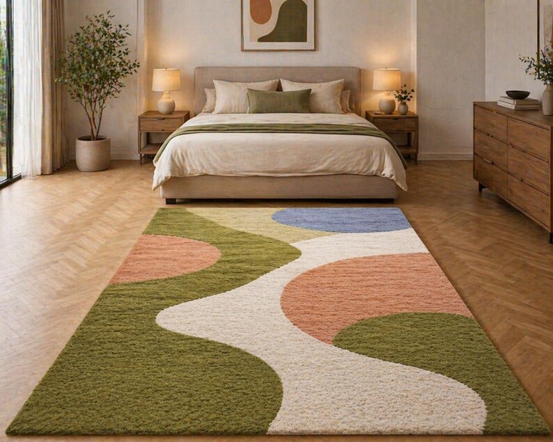 K&ouml;nnte beinhalten: Ein farbenfroher Teppich mit abstraktem Design in einem Schlafzimmer. Der Teppich hat ein wellenf&ouml;rmiges Muster mit gr&uuml;nen, pfirsichfarbenen, wei&szlig;en und blauen Abschnitten. Das Schlafzimmer umfasst ein Bett mit neutraler Bettw&auml;sche, Holzm&ouml;bel und eine Topfpflanze.