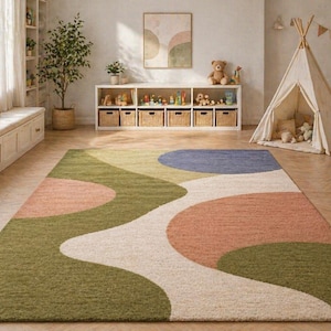 K&ouml;nnte beinhalten: Ein farbenfroher Teppich mit einem abstrakten Design in Gr&uuml;n-, Pfirsich-, Wei&szlig;- und Blaut&ouml;nen. Der Teppich befindet sich in einem Kinderspielzimmer, mit einem Tipi, Spielzeug und einem h&ouml;lzernen Schaukelpferd im Hintergrund. Der Teppich misst ca. 244 x 305 cm.
