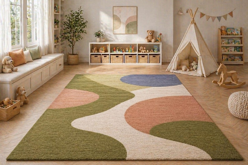 K&ouml;nnte beinhalten: Ein farbenfroher Teppich mit einem abstrakten Design in Gr&uuml;n-, Pfirsich-, Wei&szlig;- und Blaut&ouml;nen. Der Teppich befindet sich in einem Kinderspielzimmer, mit einem Tipi, Spielzeug und einem h&ouml;lzernen Schaukelpferd im Hintergrund. Der Teppich misst ca. 244 x 305 cm.