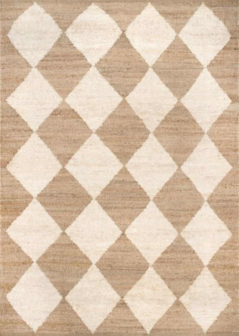 May include: A rectangular rug with a repeating diamond pattern. The design features alternating diamonds in off-white and tan, creating a textured, geometric pattern. The rug appears to be made of natural fibers.