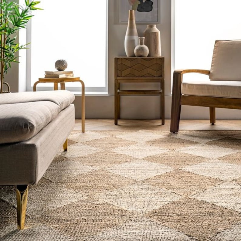 May include: A neutral-toned area rug with a geometric diamond pattern. The rug is made of natural fibers and has a textured appearance. The room also features a sofa, side table, and wooden furniture, creating a cozy living space.