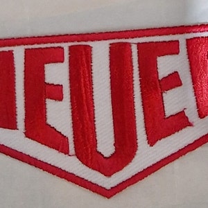 May include: Red embroidered patch with the word "HEUER" in white outlined letters.