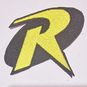 May include: Yellow and black embroidered iron-on patch featuring the letter "R" in a stylised design.