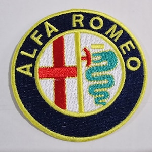 Puede incluir: Un parche bordado con el logotipo de Alfa Romeo. El logotipo es amarillo y azul con una cruz roja y una serpiente verde.