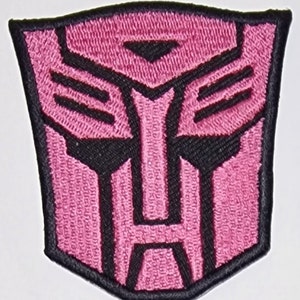 May include: Pink and black embroidered patch of the Transformers Autobot symbol.