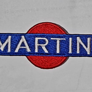 Peut inclure: Un patch brodé rouge et bleu avec le mot "MARTINI" en lettres blanches.