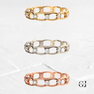 May include: Three delicate rings with a chain-link design and small diamonds set in each link. The rings are shown in gold, silver, and rose gold.