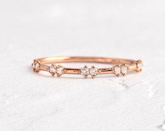 Könnte beinhalten: Ein zarter Roségold-Bandring mit einer Reihe kleiner, funkelnder Diamanten.