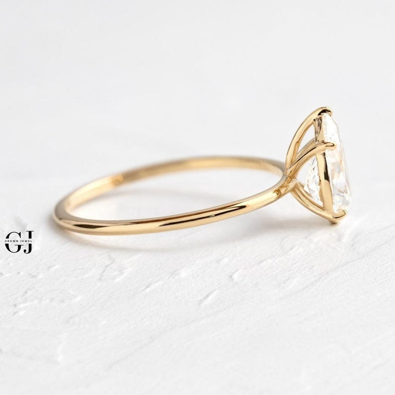 Puede incluir: Un anillo de compromiso solitario de oro con un gran diamante de forma ovalada engastado en una garra de cuatro puntas.