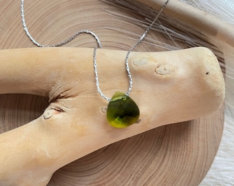 May include: A silver chain necklace with a teardrop-shaped green pendant.