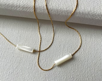 May include: A gold chain necklace with two white rectangular shell pendants.