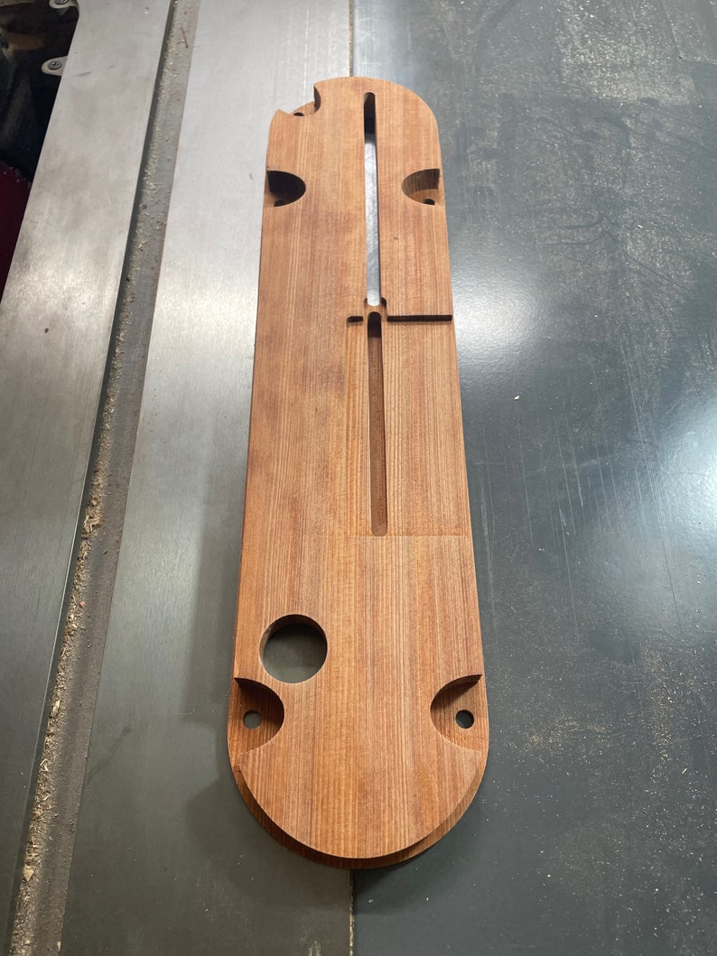 K&ouml;nnte beinhalten: Eine Holzvorlage mit Ausschnitten f&uuml;r eine Fr&auml;svorrichtung. Die Vorlage ist aus hellbraunem Holz gefertigt und hat eine glatte Oberfl&auml;che.