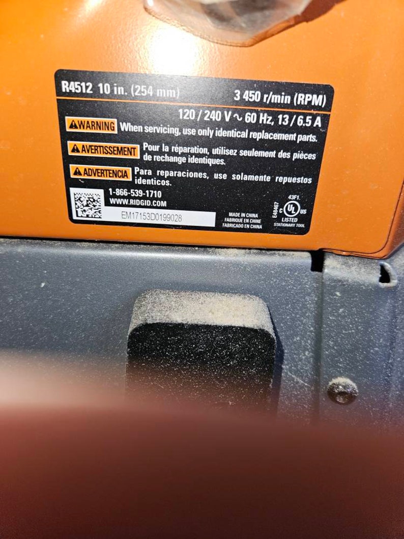 Op de afbeelding: Een zwart en oranje waarschuwingsetiket met witte tekst. Het etiket is voor een elektrisch gereedschap en bevat het modelnummer R4512, de maat 10 inch (254 mm), de spanning 120/240 V, de frequentie 60 Hz, de stroomsterkte 13/6,5 A en de snelheid 3.450 tpm (RPM). Het etiket bevat ook een waarschuwing in het Engels, Frans en Spaans om bij het onderhouden van het gereedschap alleen identieke vervangende onderdelen te gebruiken.