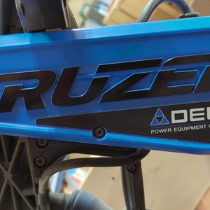 May include: Close-up of a blue and black power tool with the words "CRUZER" and "DELTA POWER EQUIPMENT CORPORATION" printed on it.