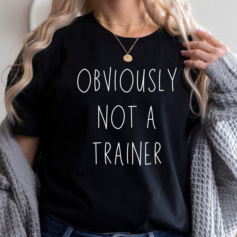 May include: Black crew neck t-shirt with the white text "OBVIOUSLY NOT A TRAINER".