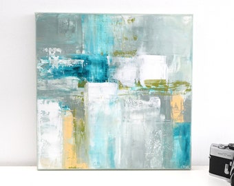 Op de afbeelding: Abstract schilderij op canvas met tinten blauw, groen, grijs en wit. Het schilderij heeft een textuur en is ingelijst in een wit frame.