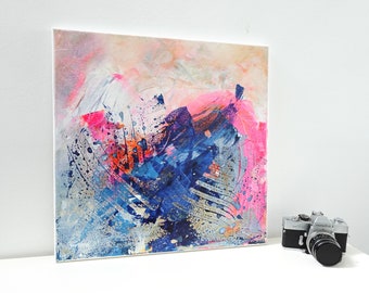 Op de afbeelding: Abstract schilderij op canvas met roze, blauwe, witte en gouden verfspatten en penseelstreken.