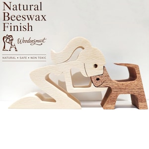 May include: A light-colored wooden figurine of a person kneeling and interacting with a darker-colored wooden dog figurine. The text "Natural Beeswax Finish" and "Woodensmart" is visible in the upper left corner, along with "NATURAL • SAFE • NON TOXIC".