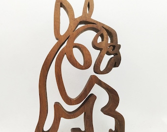 Op de afbeelding: Een houten sculptuur van een Franse Bulldog, gesneden in een minimalistische stijl. Het beeld is bruin en heeft een gladde afwerking.