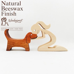 Può includere: Un set di statuette in legno raffigurante una persona di colore chiaro in ginocchio e un cane marrone rossiccio. Il testo sull'immagine recita: Natural Beeswax Finish, Woodensmart, NATURAL • SAFE • NON TOXIC. Le figure sono in legno liscio.