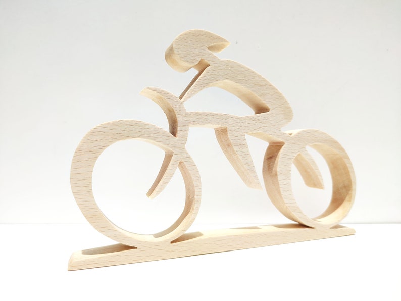 Peut inclure: Sculpture en bois repr&eacute;sentant un cycliste sur un v&eacute;lo. La sculpture est faite de bois clair et pr&eacute;sente un design minimaliste. Les roues et le cadre du v&eacute;lo sont stylis&eacute;s, et le cycliste est en position de conduite. La sculpture est mont&eacute;e sur une base rectangulaire.