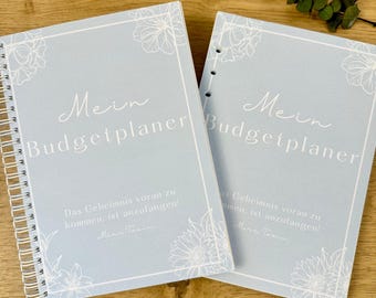 May include: Two light blue spiral bound notebooks with the text "Mein Budgetplaner" and a floral design. The text "Das Geheimnis voran zu kommen, ist anzufangen!" is printed below the title.