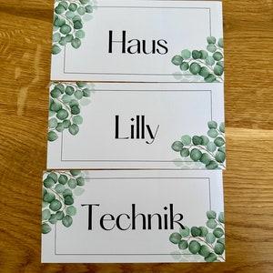 Könnte beinhalten: Drei weiße Karten mit schwarzem Text und grünen Eukalyptus-Blatt-Illustrationen. Die Karten lauten "Haus", "Lilly" und "Technik".