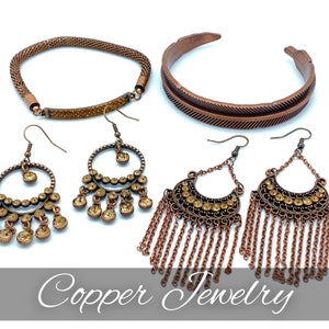 May include: A set of copper jewelry featuring a bracelet, a pair of earrings with dangling chains, and a pair of hoop earrings with crystal accents. The jewelry is on a white background. Copper Jewelry.