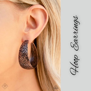 May include: Copper hoop earrings with an intricate floral pattern. The earrings are large and have a rustic look.